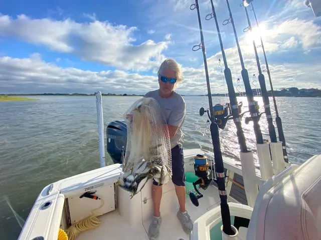 Young angler showing his catch beside the fishing rods