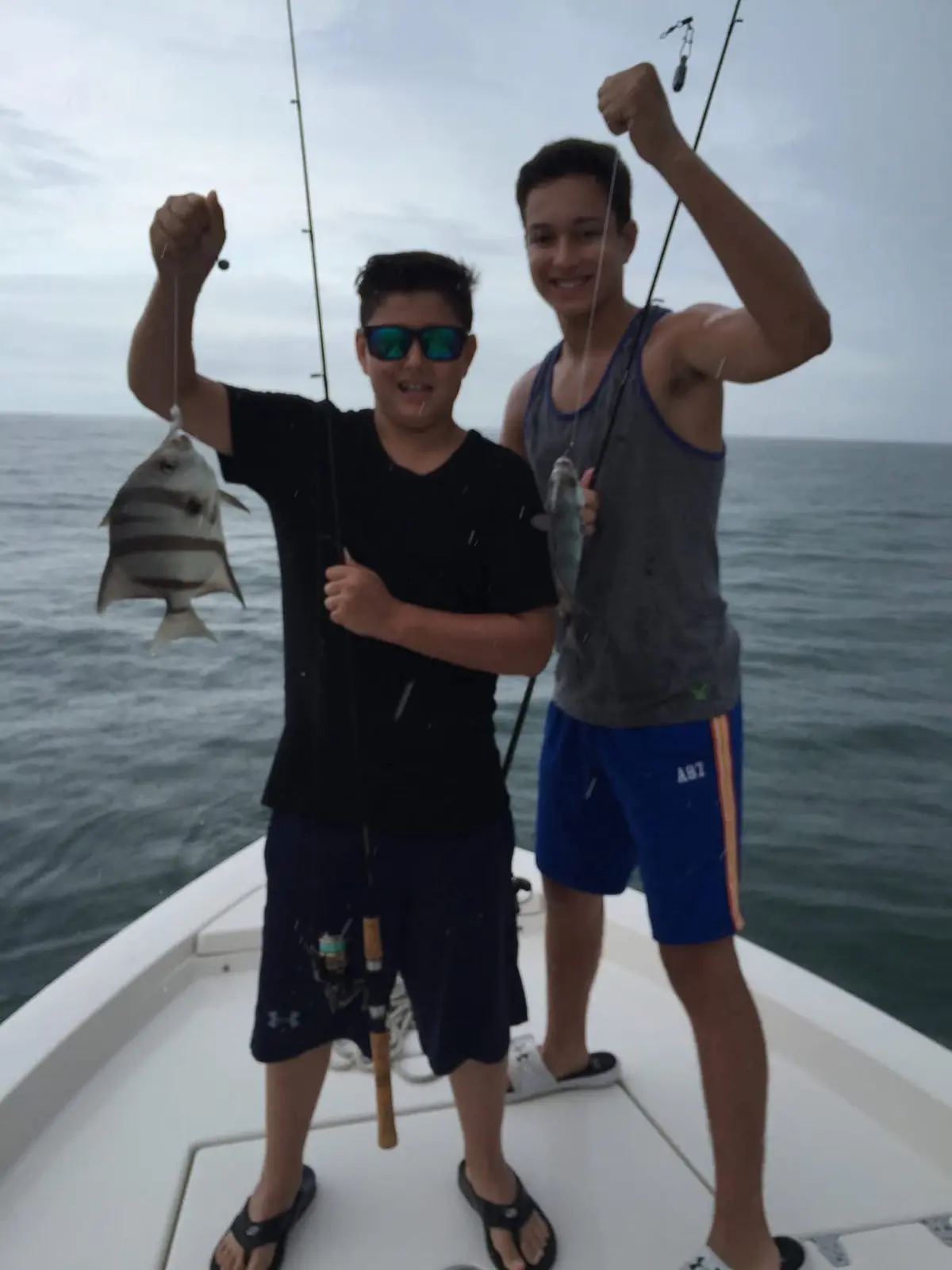 Two young anglers celebrating their catches aboard the boat