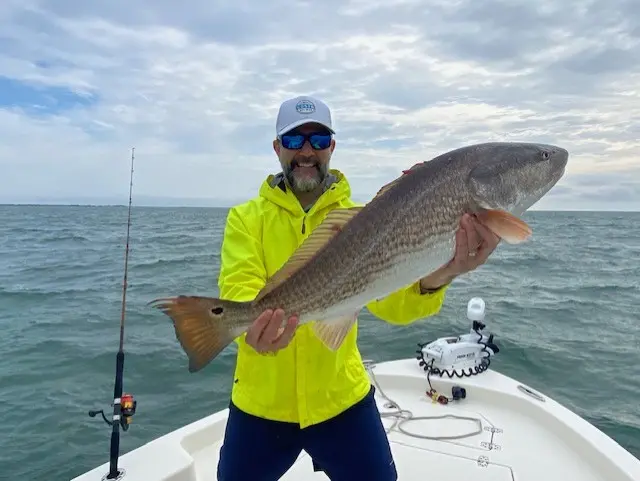 Angler in a bright jacket holding a redfish near Charleston