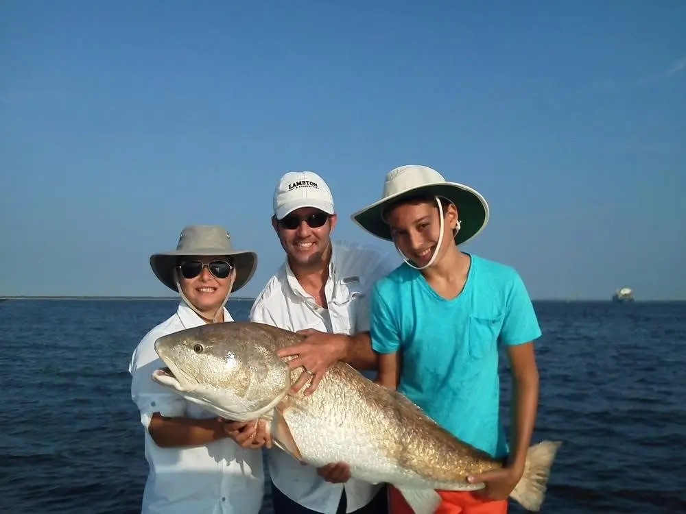 Three anglers together holding a large fish