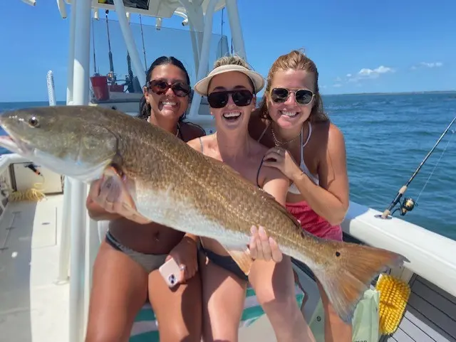 Three guests laughing together while holding a large fish